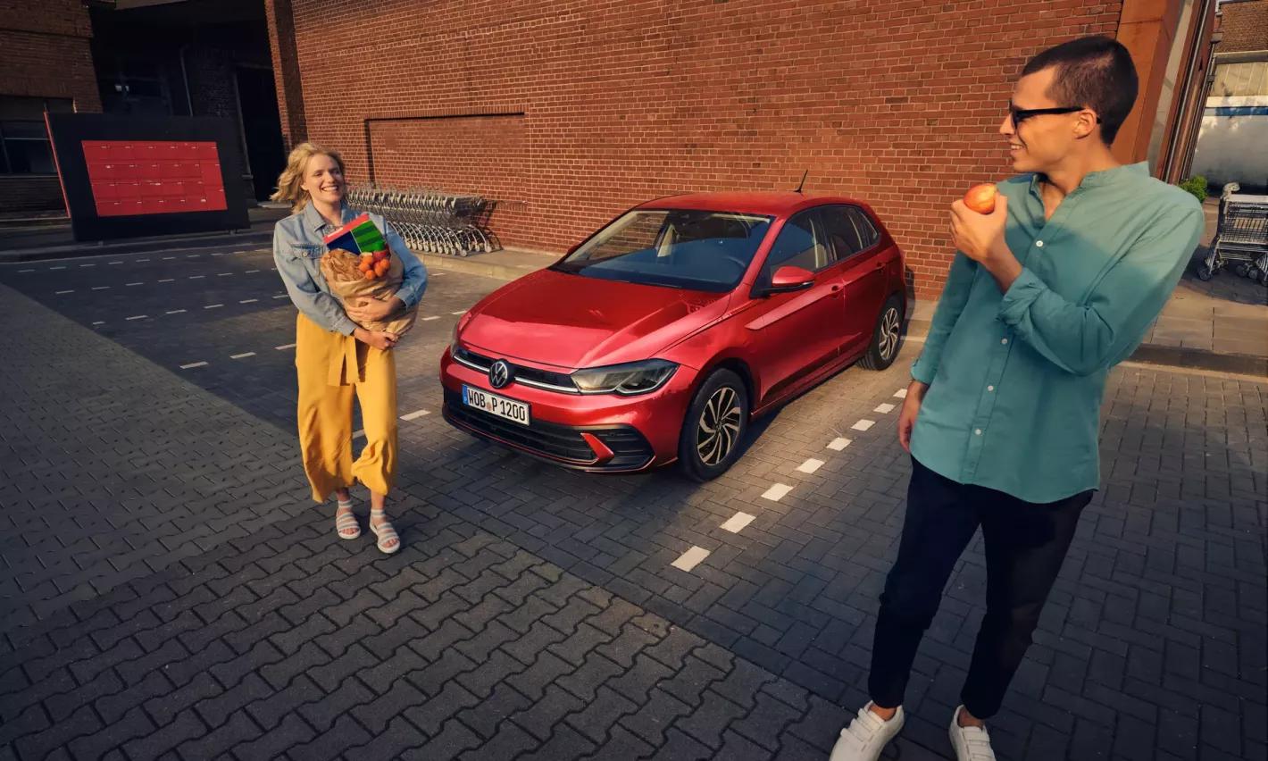 2 mensen rond een rode Volkswagen Polo